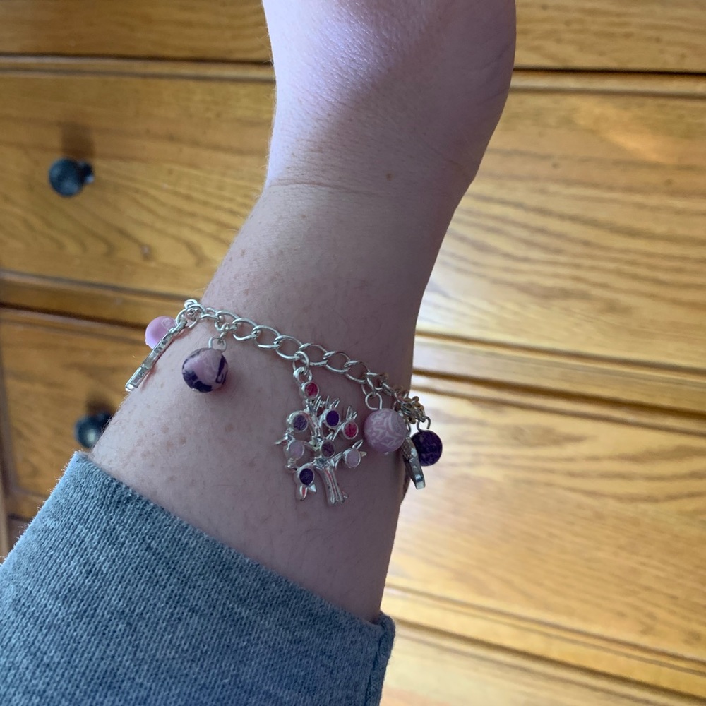 Silver bracelet with pink and purple charms.